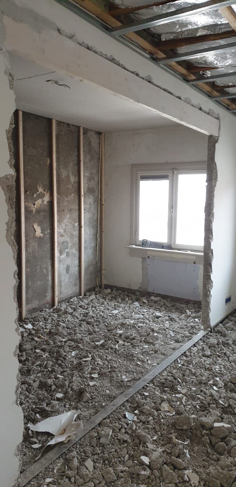 Slaapkamer in een bestaande woning tijdens de sloop: kale muren en puin op de vloer