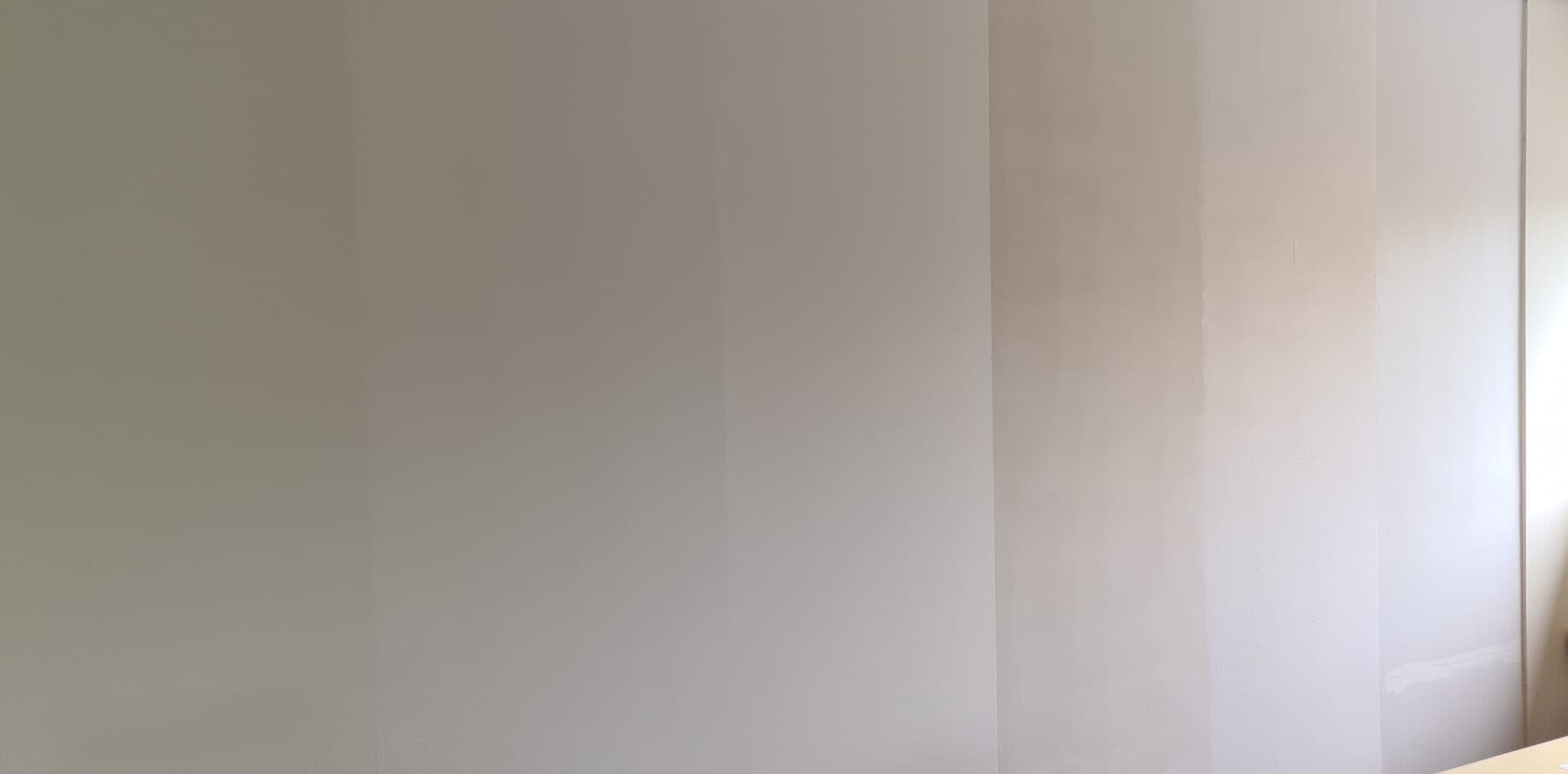 Muur met verschillende lagen van renovlies behang in het opbouwproces.